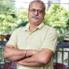 Portrait indian senior man wearing eye glasses standing cross arm indoors, Retired asian old male.